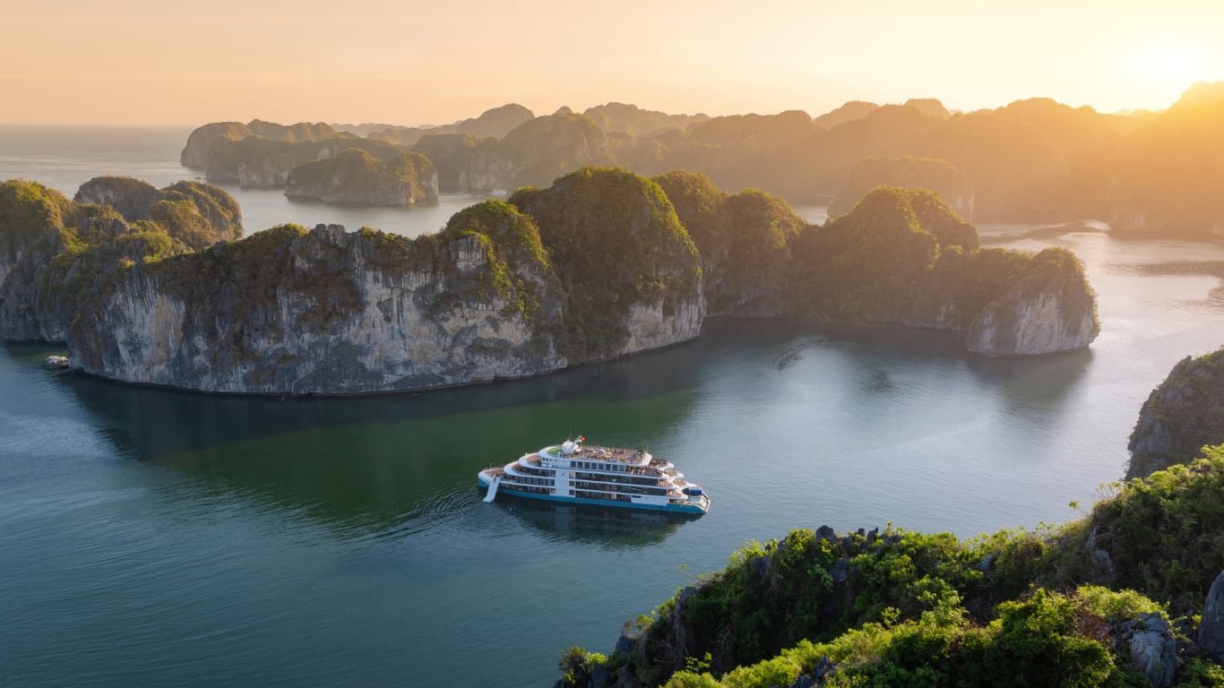 Elegant cruise ship moving through clear blue Ha Long Bay water